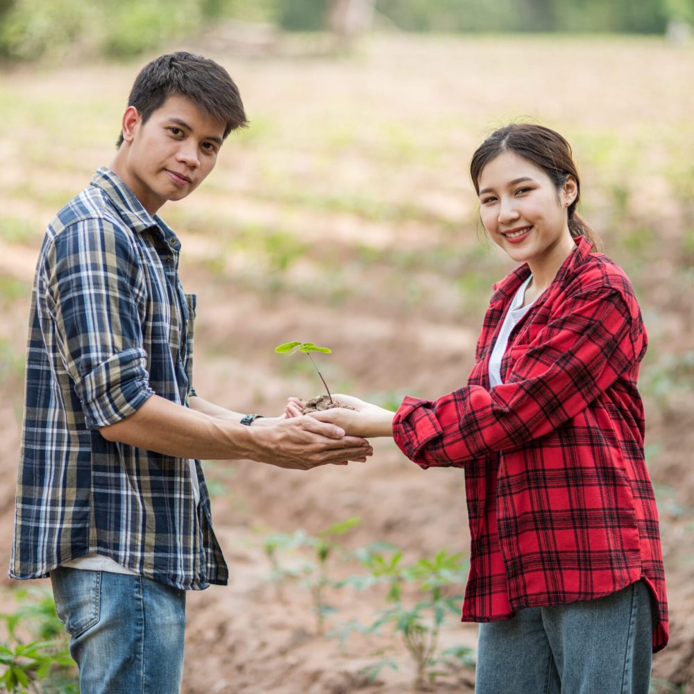 Men and women standing and holding saplings. Selective focus.